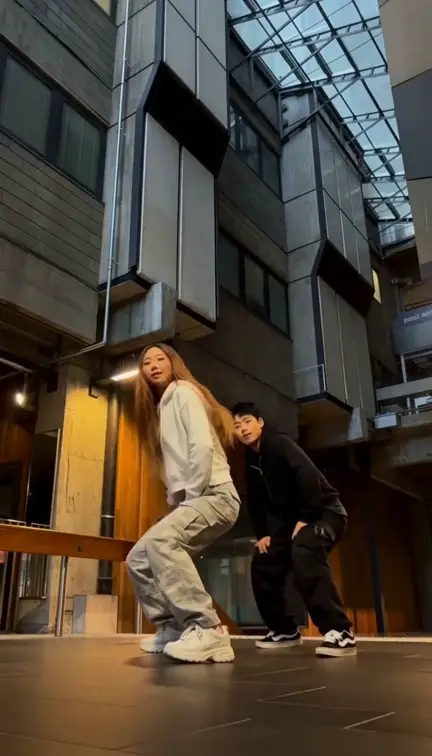 The NEON spin kick on loop: the AI-generated dancer in the white hoodie spins and high-kicks next to her partner in black